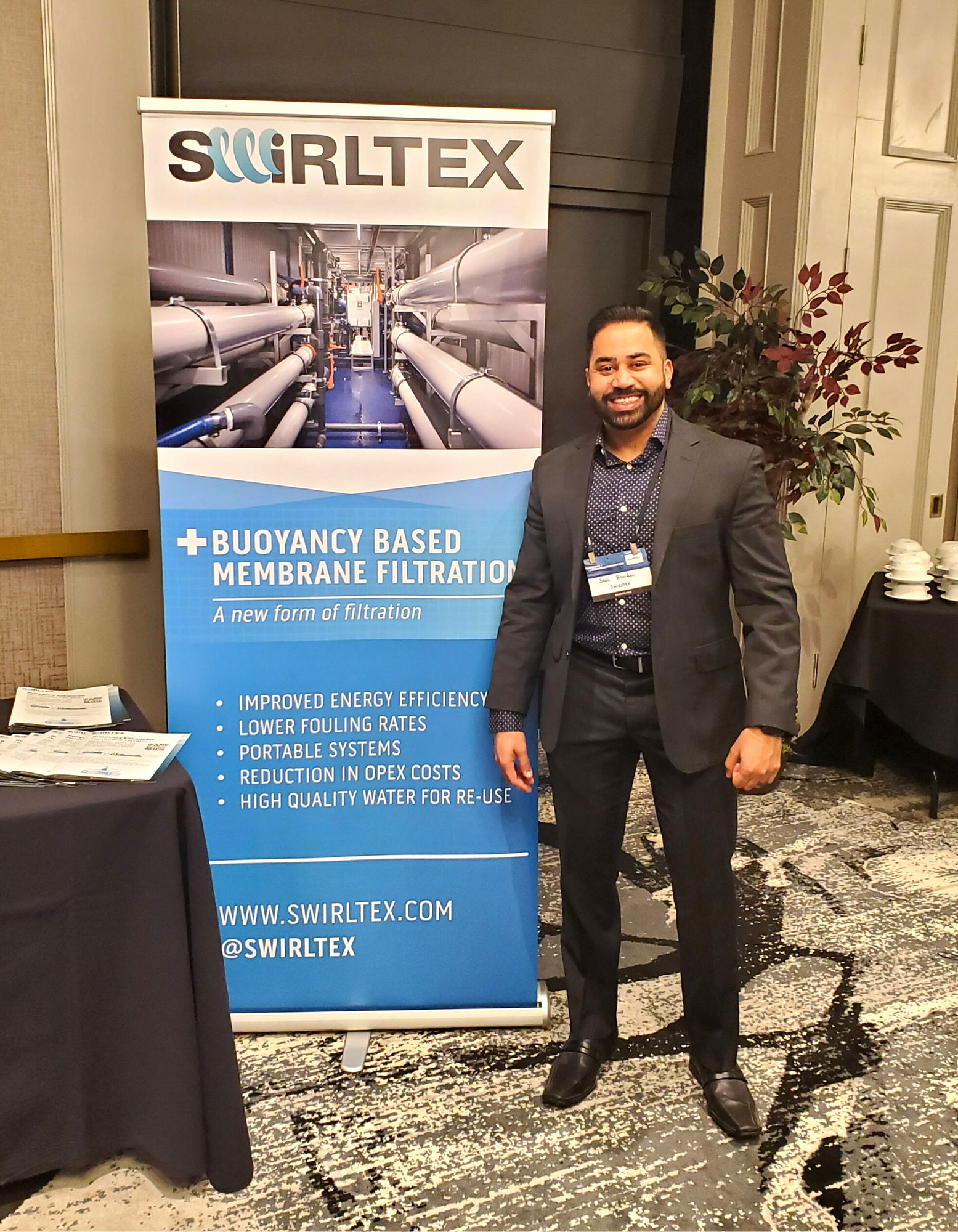 Swirltex team member standing next to banner about swirltex technology in produced water treatment
